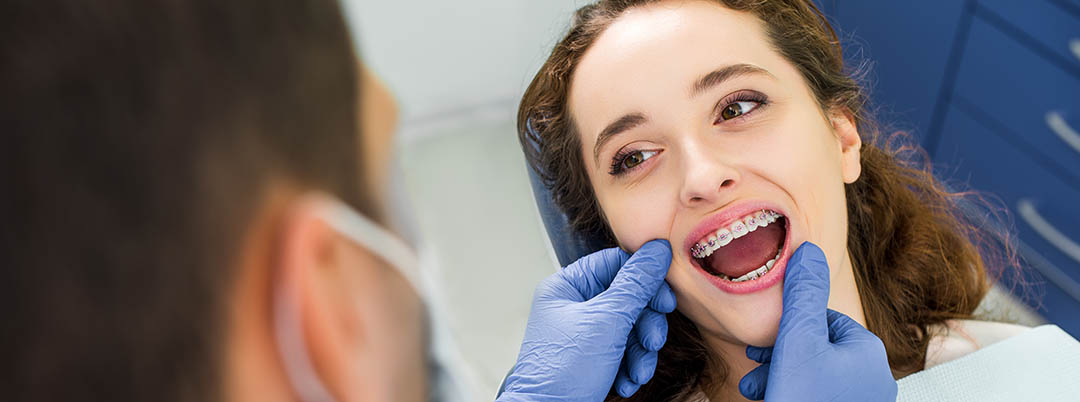 cheerful woman in braces opening mouth during examination of teeth