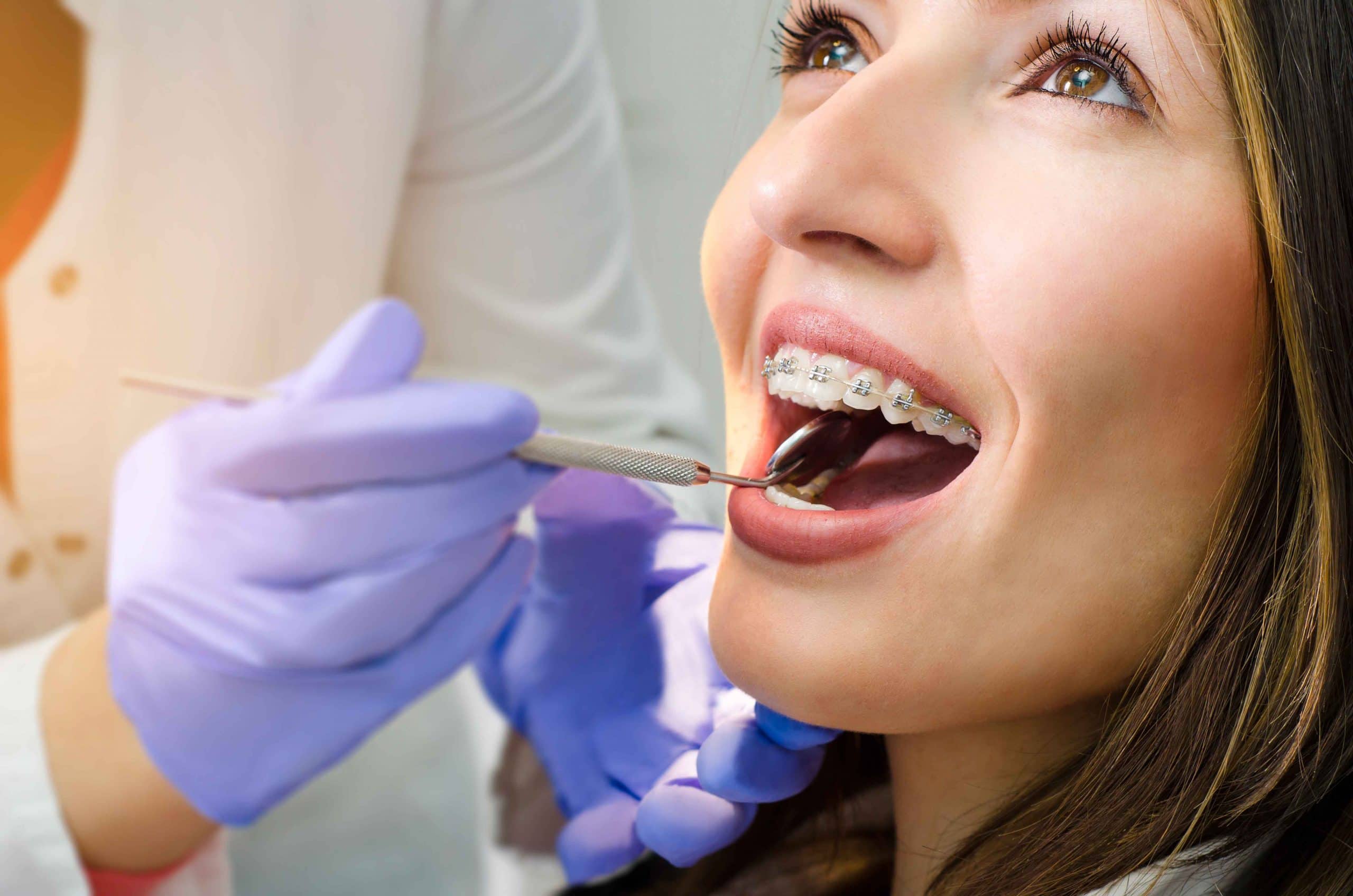 Dentist examining a female patient with braces during an orthodontic checkup. Visualizing orthodontic treatment time by age