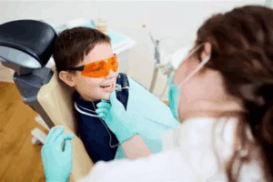Young boy wearing protective glasses during a dental checkup with a dentist