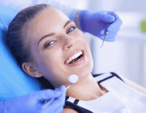Smiling female patient during a dental examination with dental tools nearby