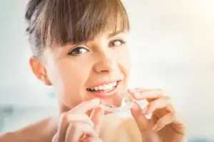 Woman smiling while wearing Invisalign clear aligners for teeth straightening