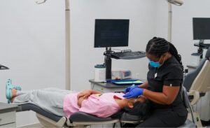 A dental hygienist or assistant treating a patient resting in a dental chair
